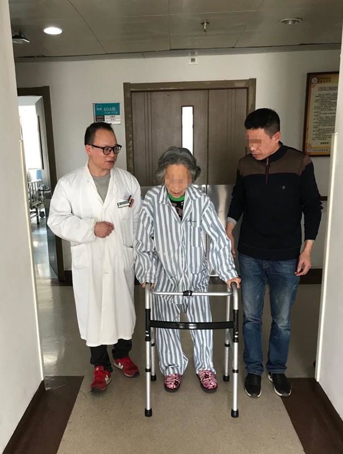 术后第二天，主管医师留成胜和家属在边上鼓励程奶奶下地行走.jpg